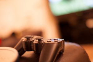 games controller sitting on a sofa arm with football game playing in background